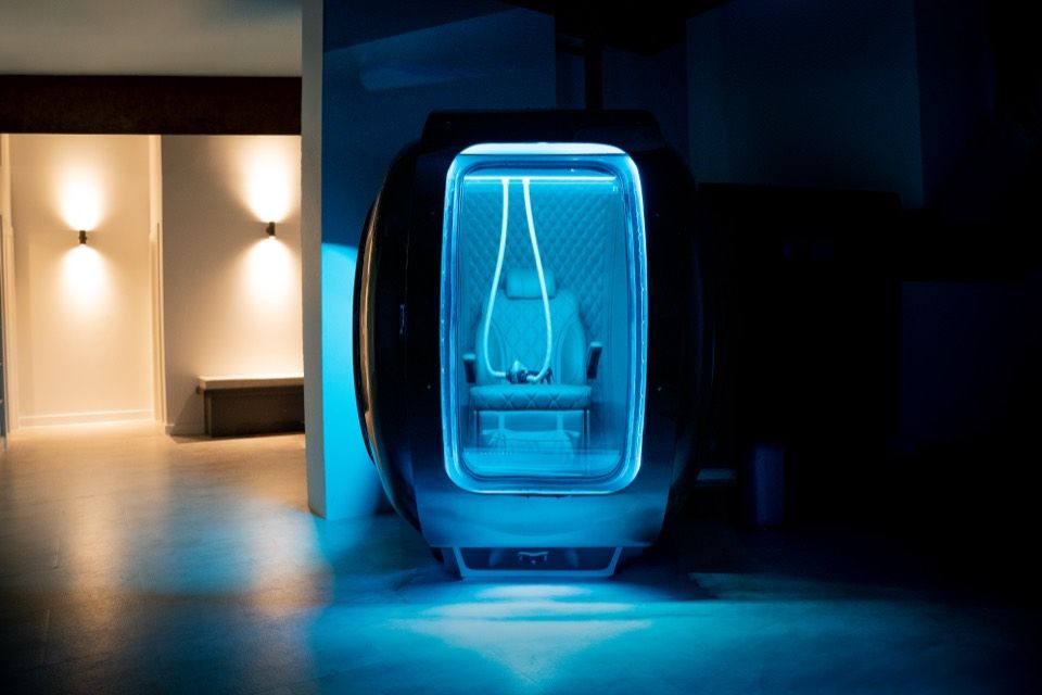 The hyperbaric chamber lit from within, standing empty in the Battersea treatment room