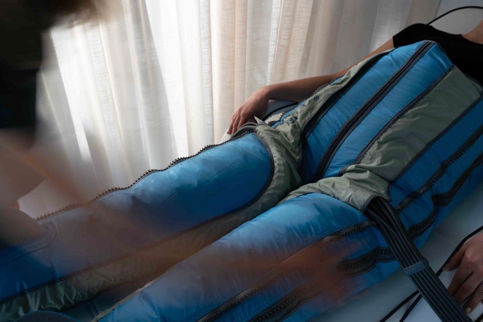 A client resting in the inflated compression trousers beside a curtained window