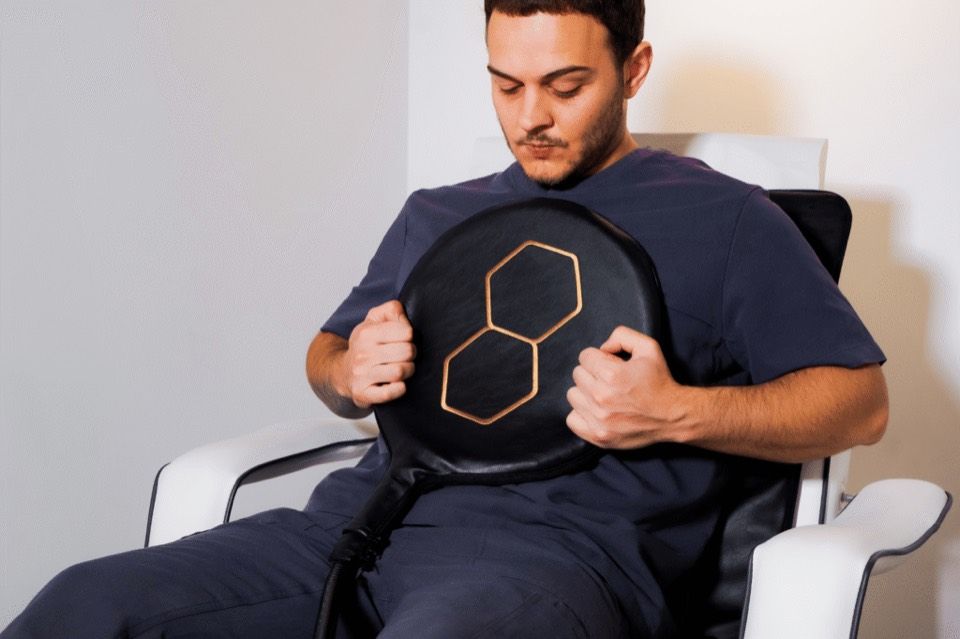 A client in a treatment chair holding the round PEMF applicator against his chest